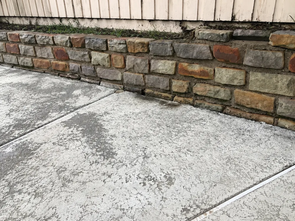 Clean stone retaining wall after pressure washing, moss removed